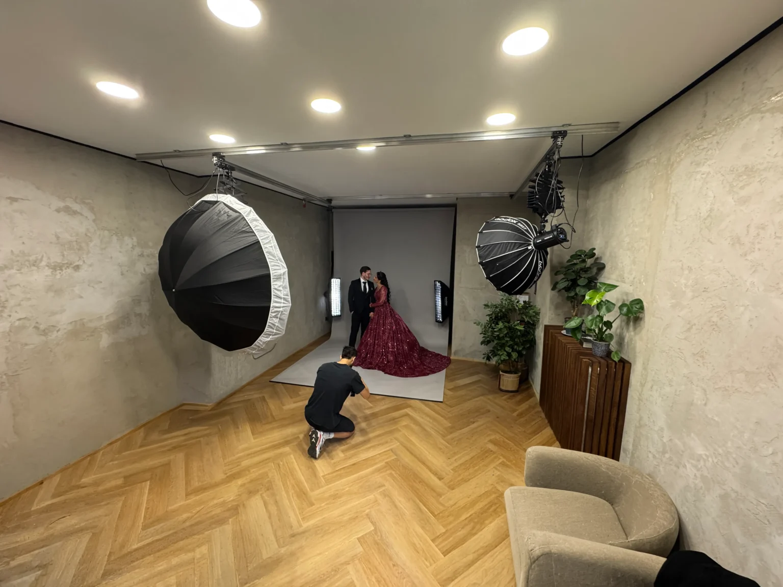 Mietstudio von Fotowest: Raum mit Parkett, grauem Hintergrund, zwei Pantografen mit großen Reflektoren und Sitzecke
